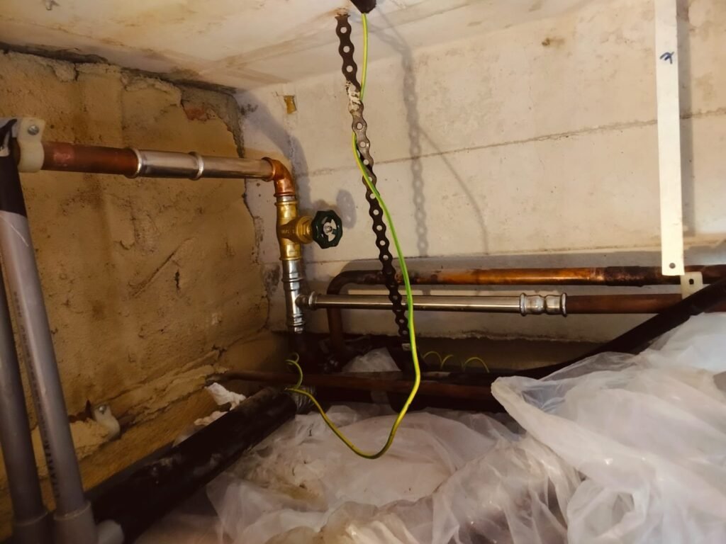 Professional PUB-licensed plumber fixing a kitchen sink pipe leak in a Singapore HDB apartment.