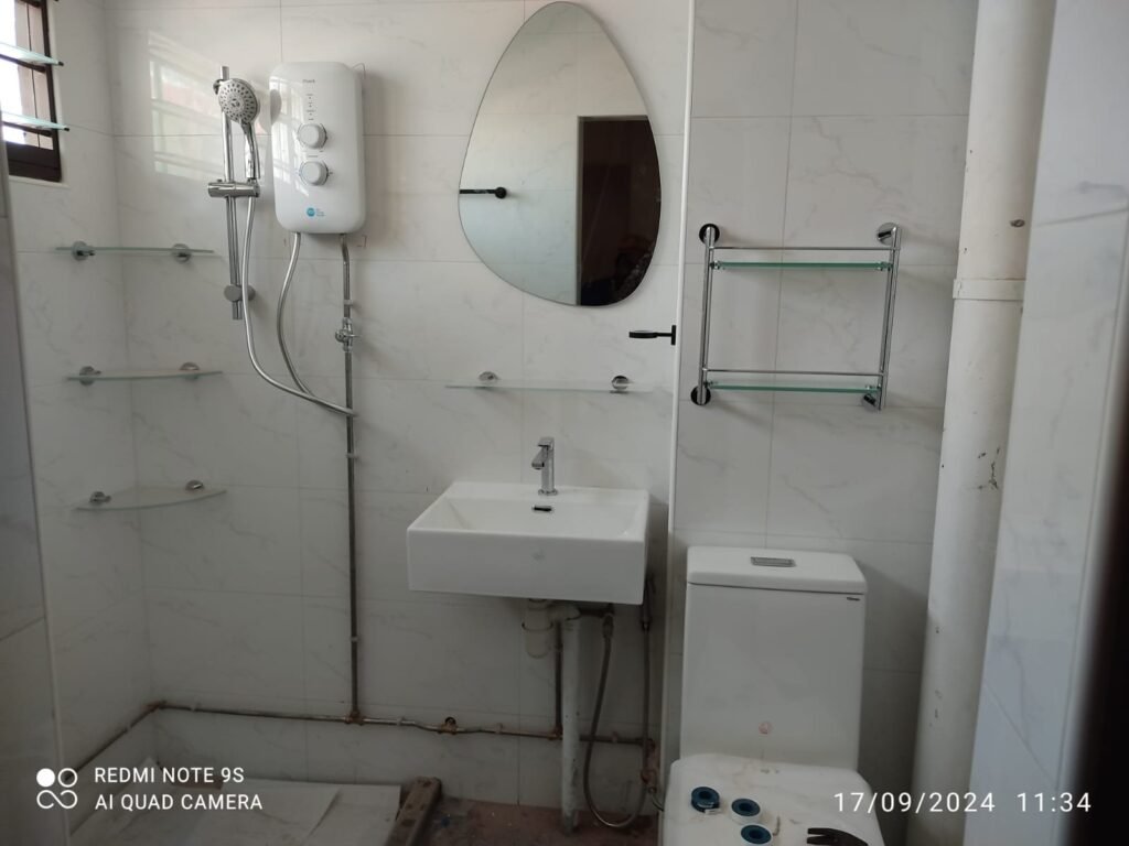 A professional plumber fixing a kitchen sink pipe leak in a Singapore HDB apartment.