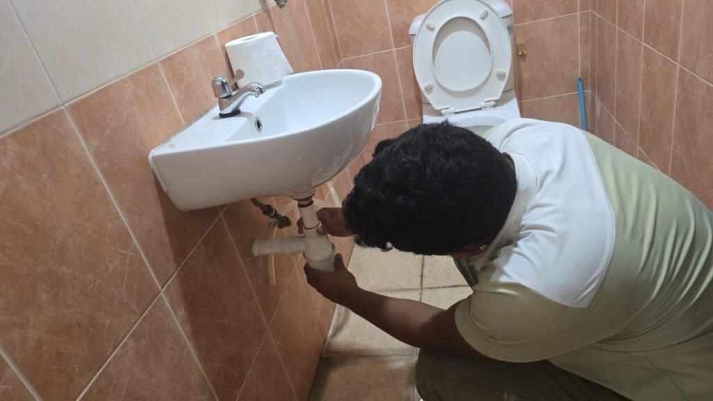 Professional PUB-licensed plumber in Singapore performing a kitchen sink drainage overhaul and pipe replacement.