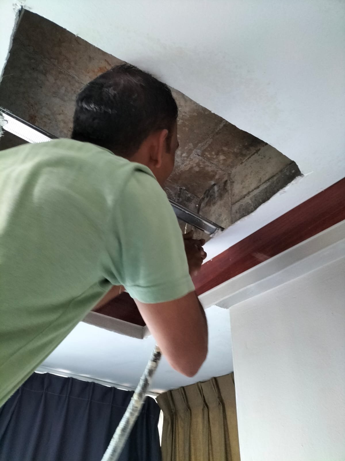 Professional using a thermal imaging camera to locate a hidden water leak in a Singapore HDB bathroom ceiling.